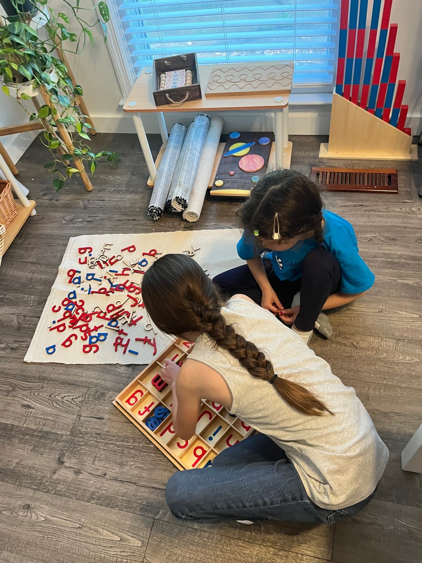 Two children building words with a movable alphabet on a floor mat