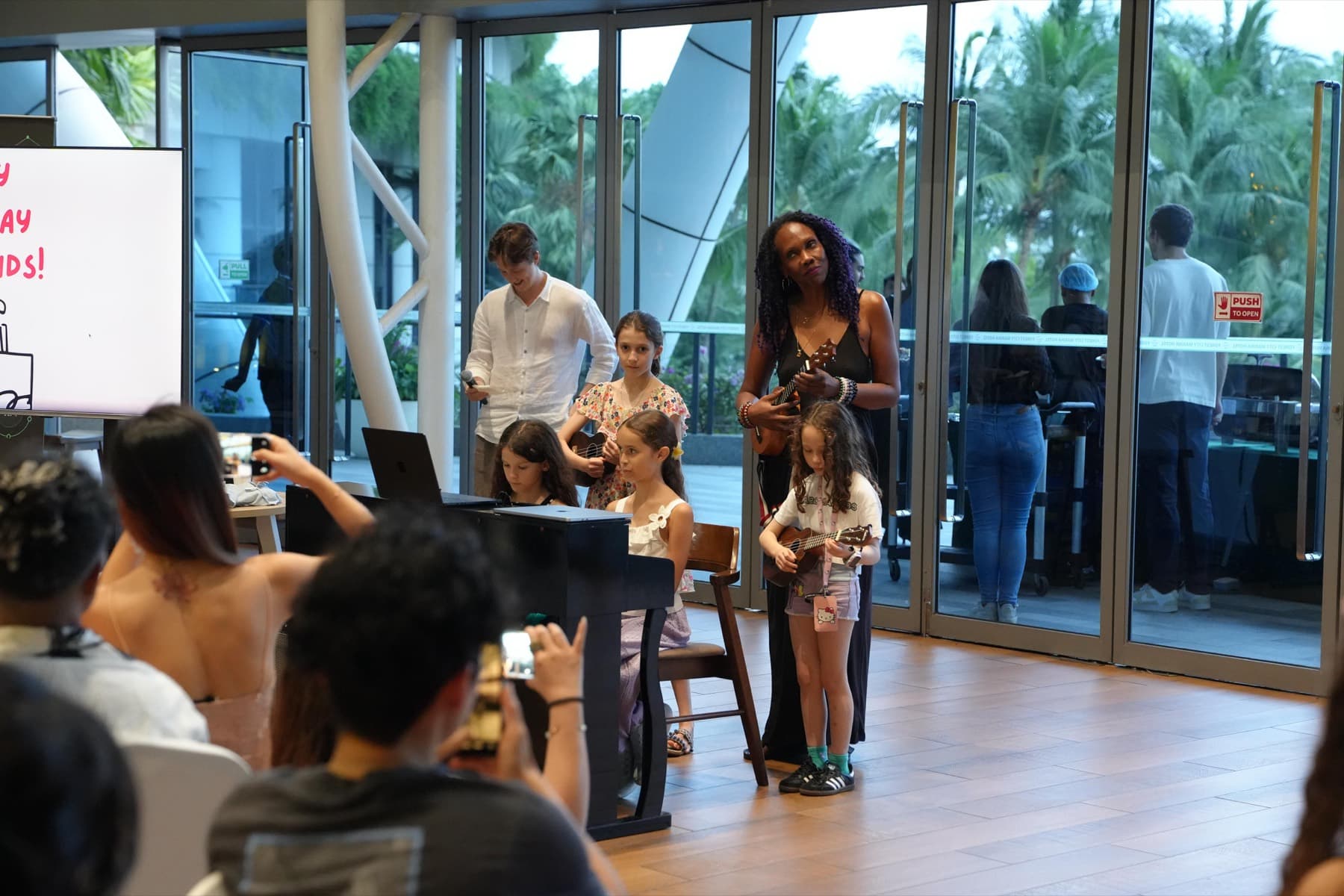 Children performing on piano and ukulele for families at a Network School community event