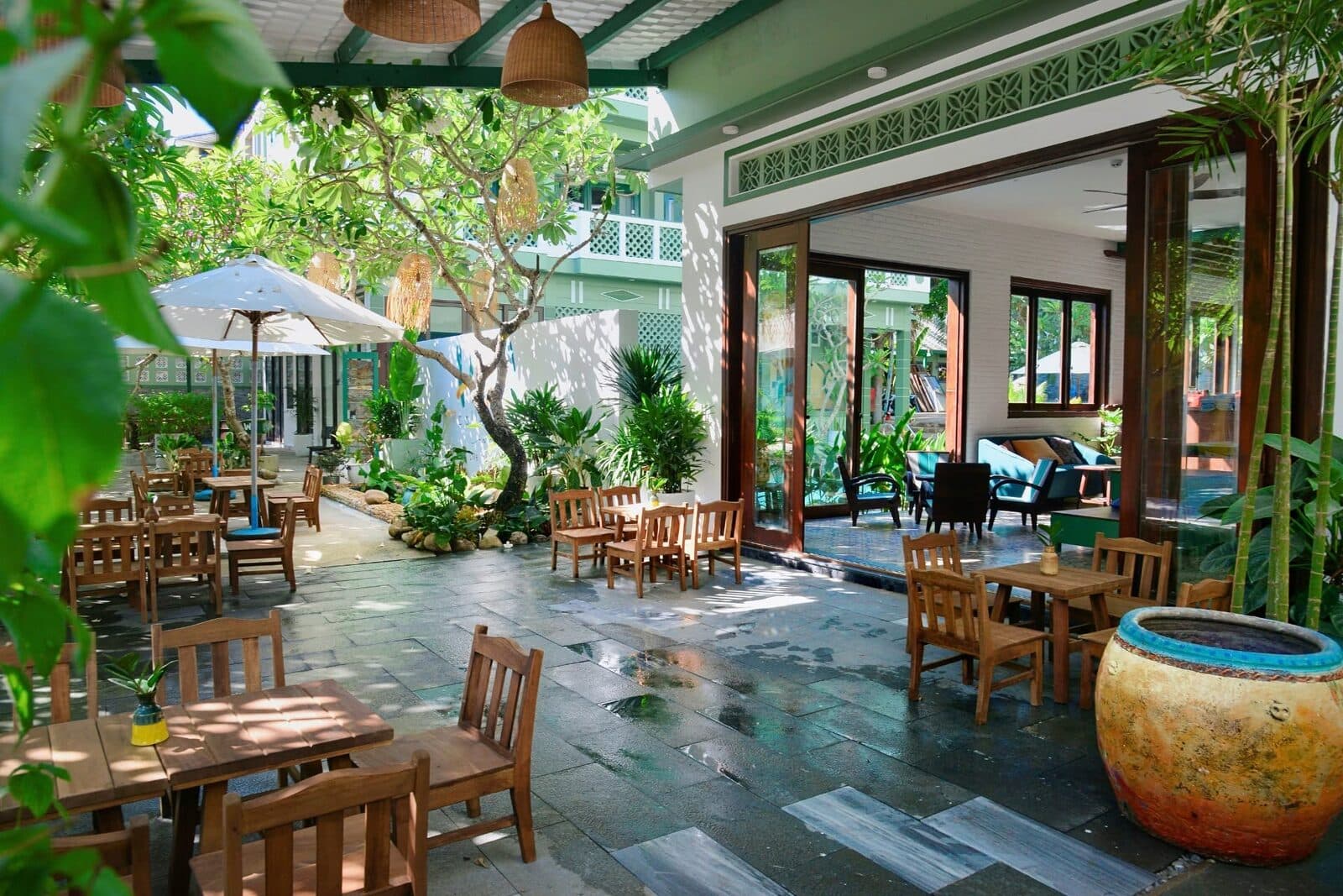 An open-air common area with wooden tables, plants, and an umbrella at the collective