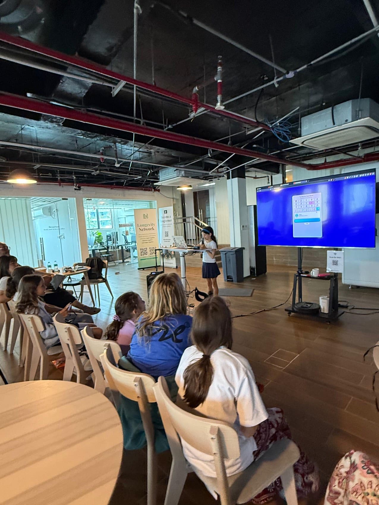 A girl presenting her app on a big screen to an audience of children at Edventures family programming