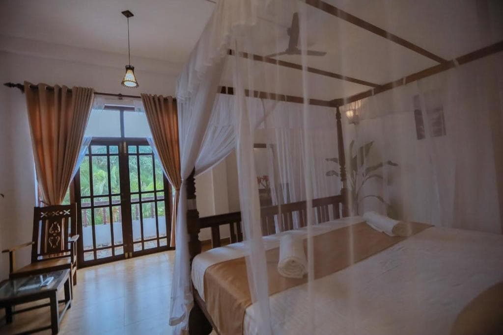 A bedroom with a four-poster canopy bed and doors opening to a balcony over the garden