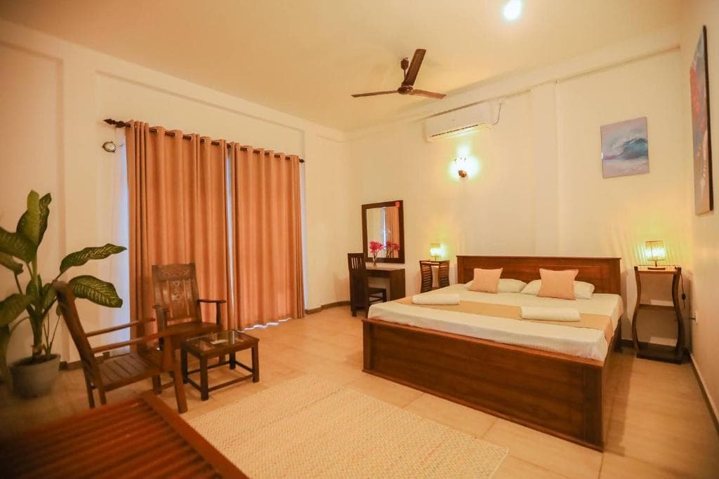 A large family room with a king bed, a ceiling fan, and a sitting corner