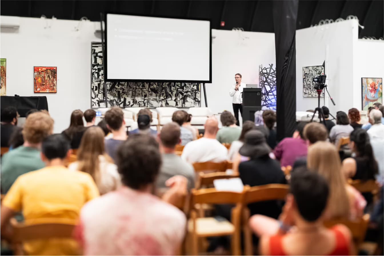 A packed evening talk at a prior Edge City village, the room full and attentive