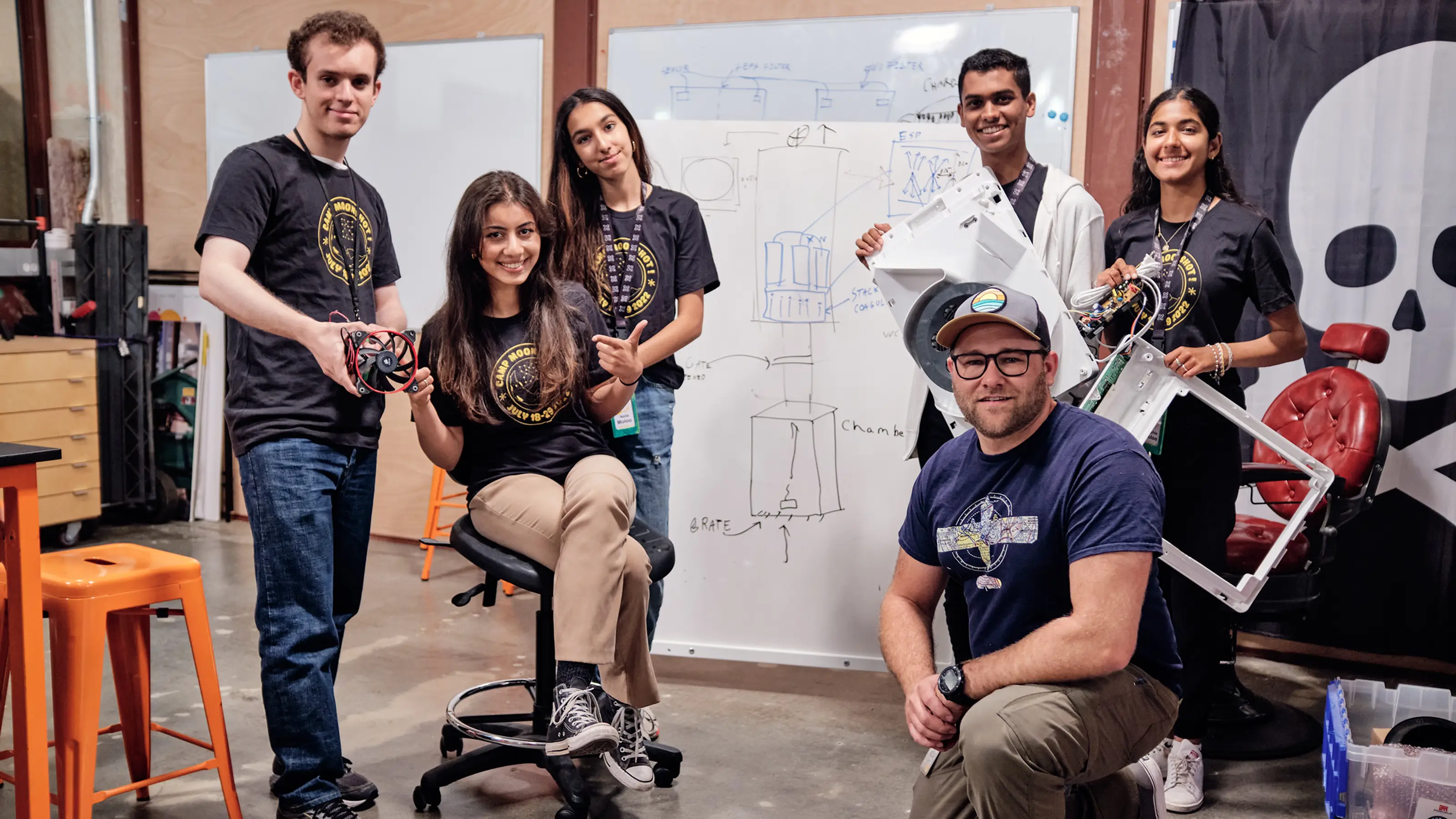 A student team at a whiteboard working on a moonshot project with hardware