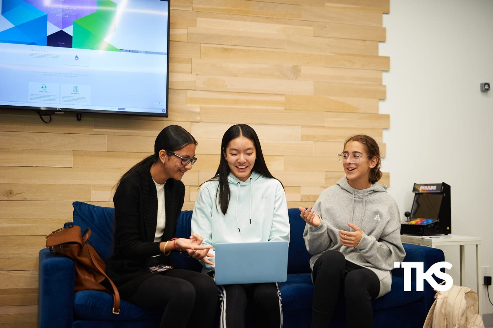 Three TKS students collaborating over a laptop